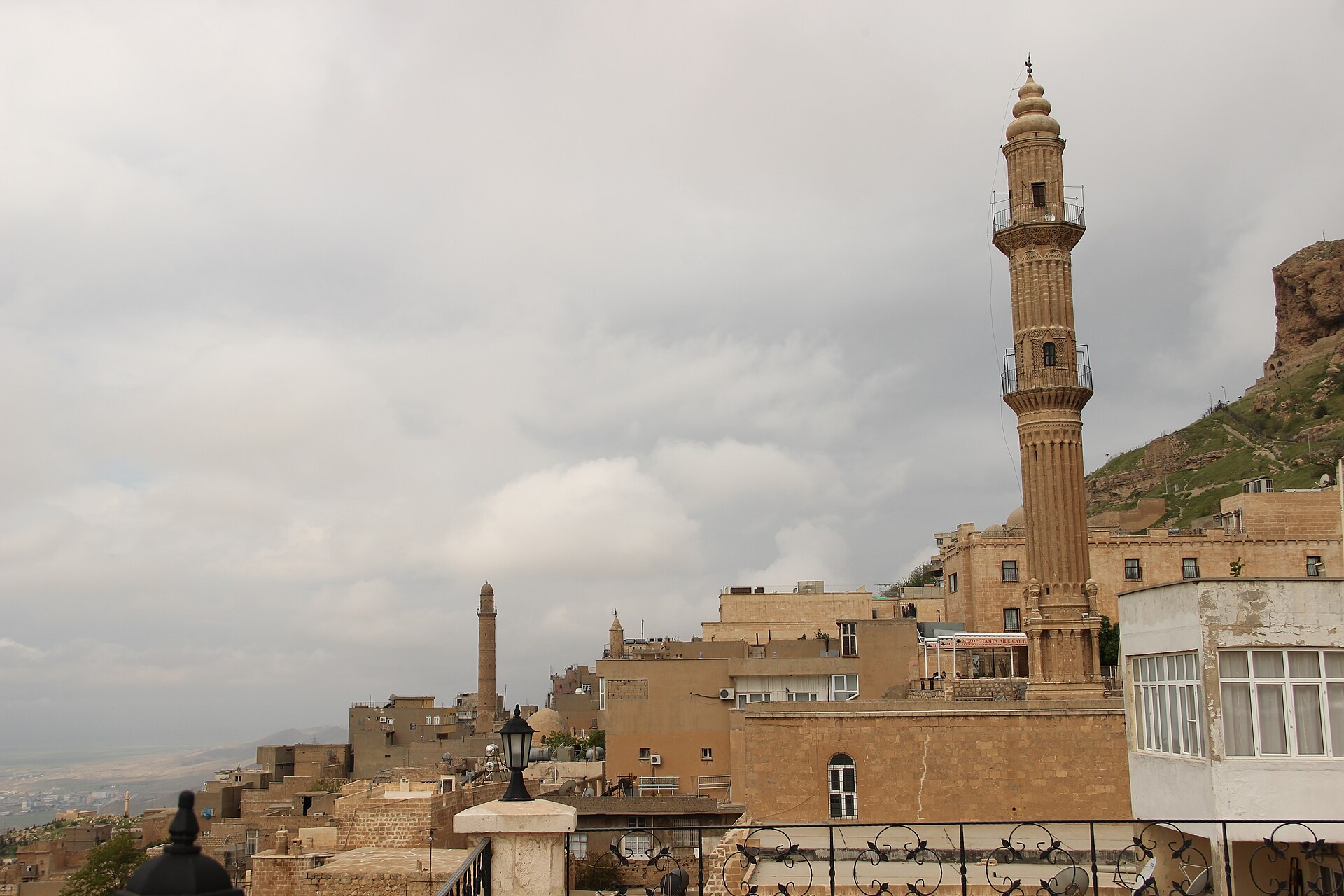 Mardin'in taş damları ve bir minare; arkada Mezopotamya ovası